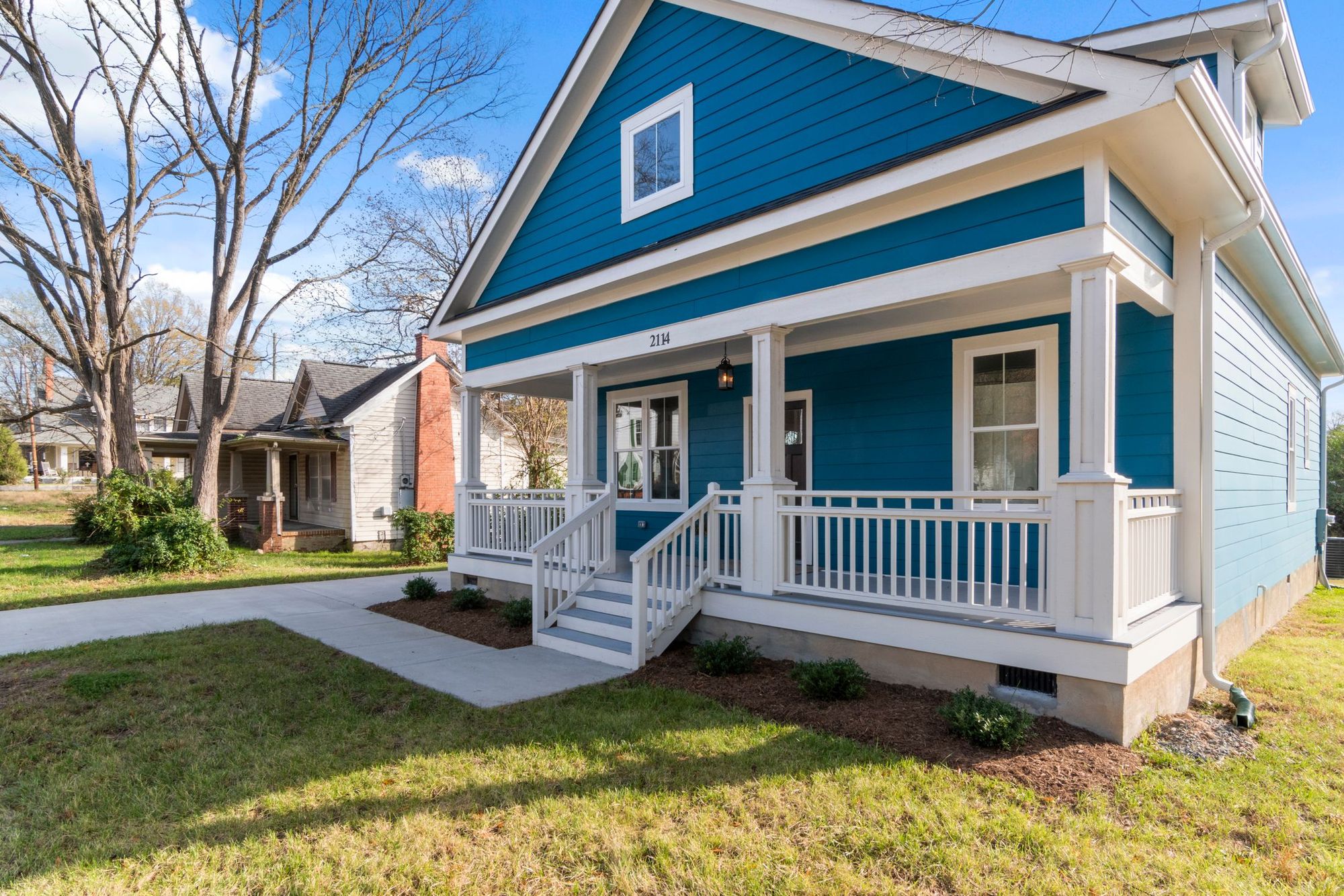 Blue bungalow with a rebuilt white front porch and railing