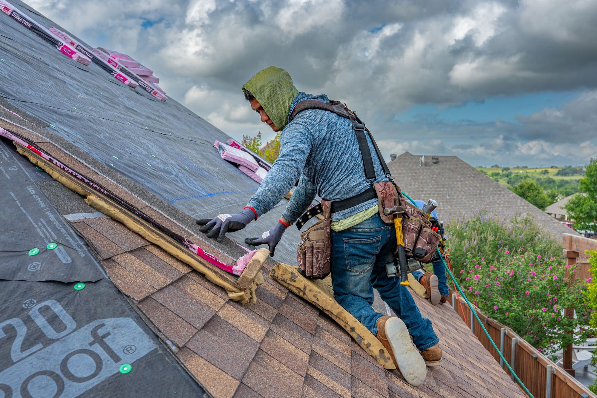 Roofer setting shingles over new underlayment