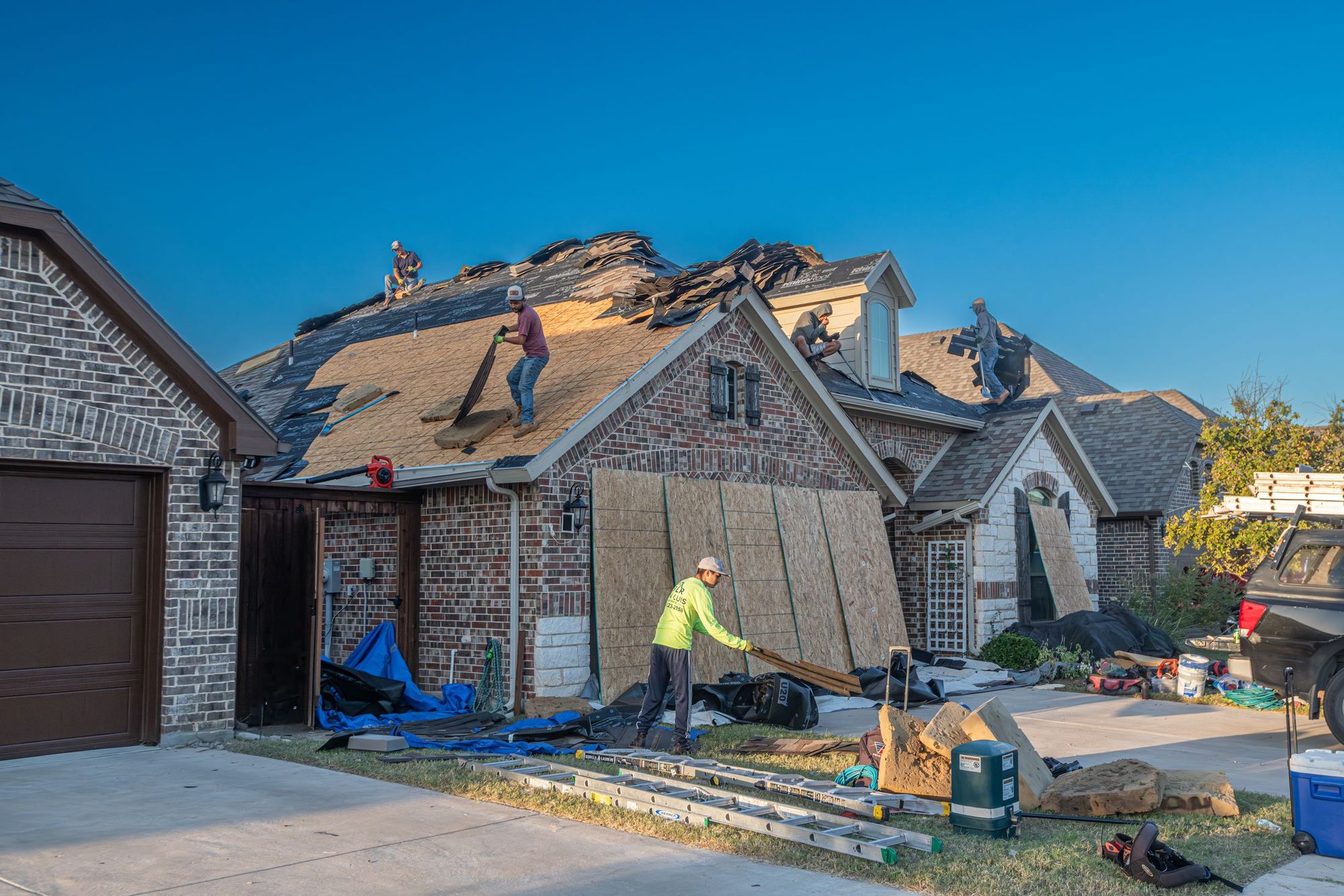 Crew tearing off and replacing the roof on a brick house