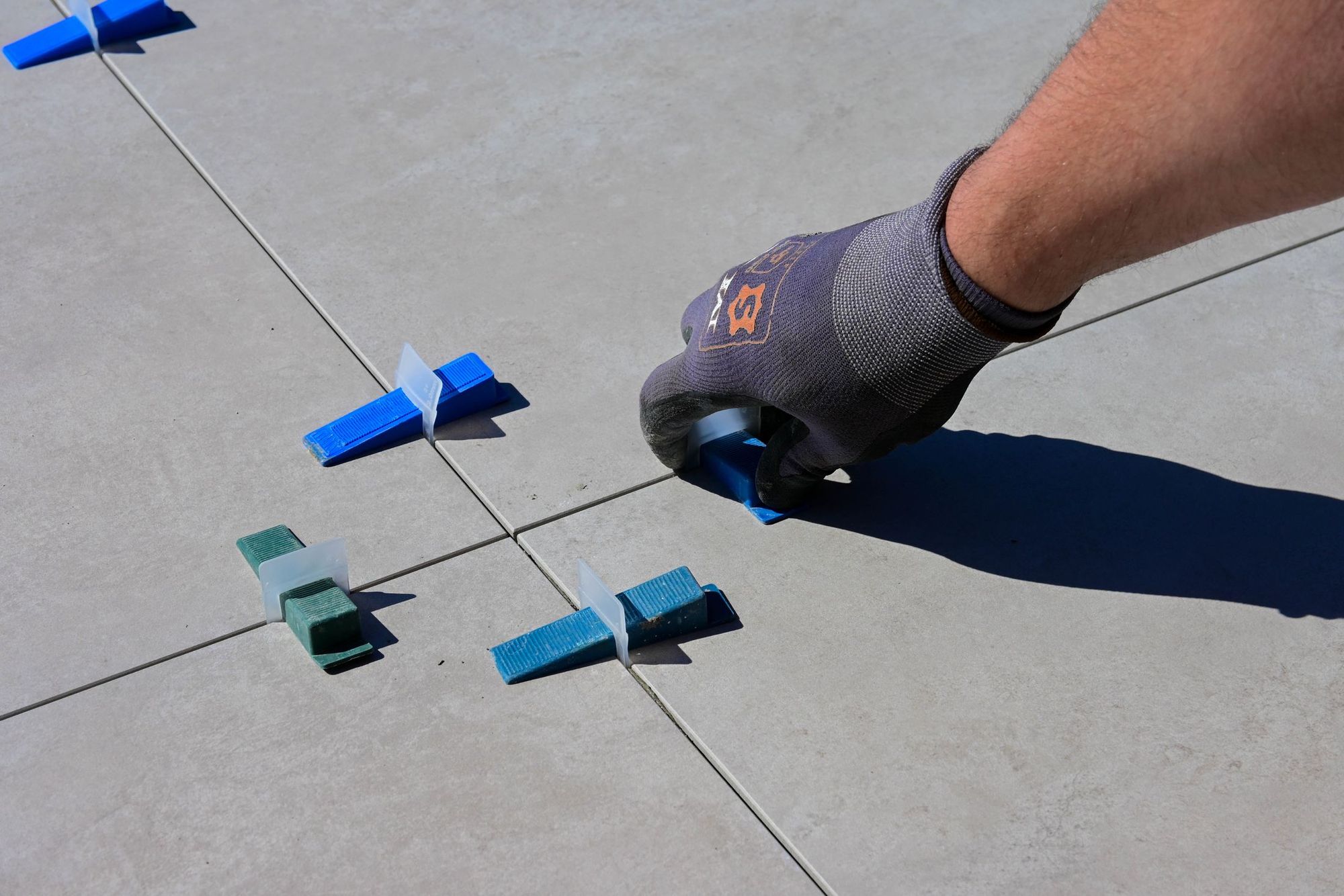 A tile setter leveling a large-format porcelain shower wall mid-installation