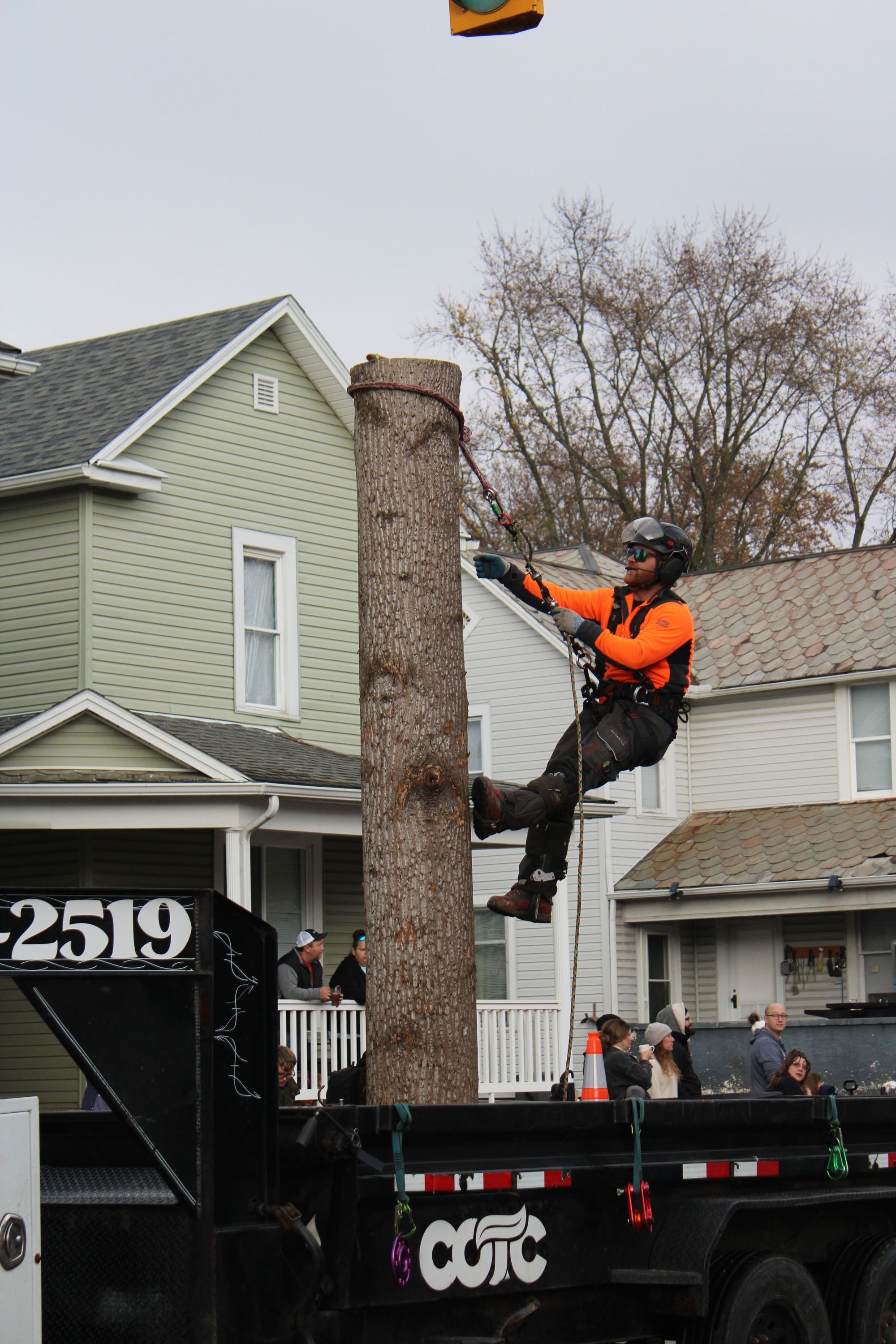 Climber cutting trunk sections beside a house