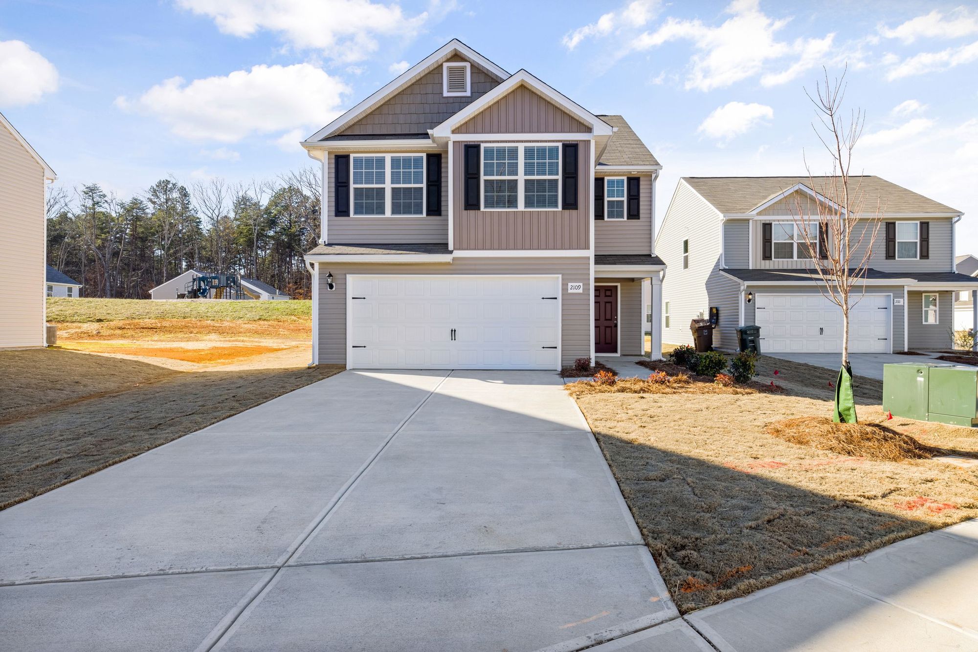 New-build front yard with bare clay on both sides of the driveway