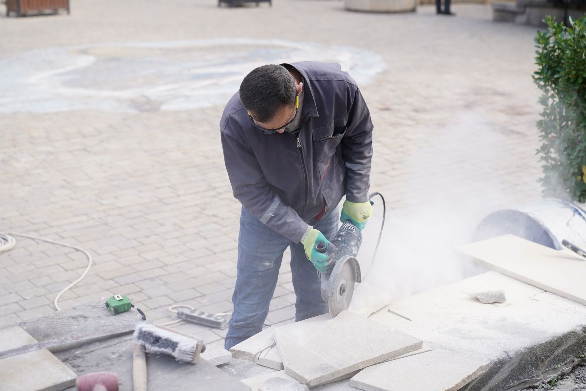 Worker cutting a stone paver with a wet saw