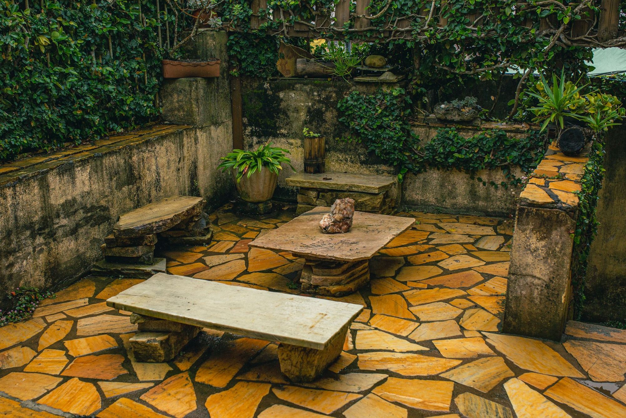 Flagstone patio with stone benches surrounded by ivy-covered walls