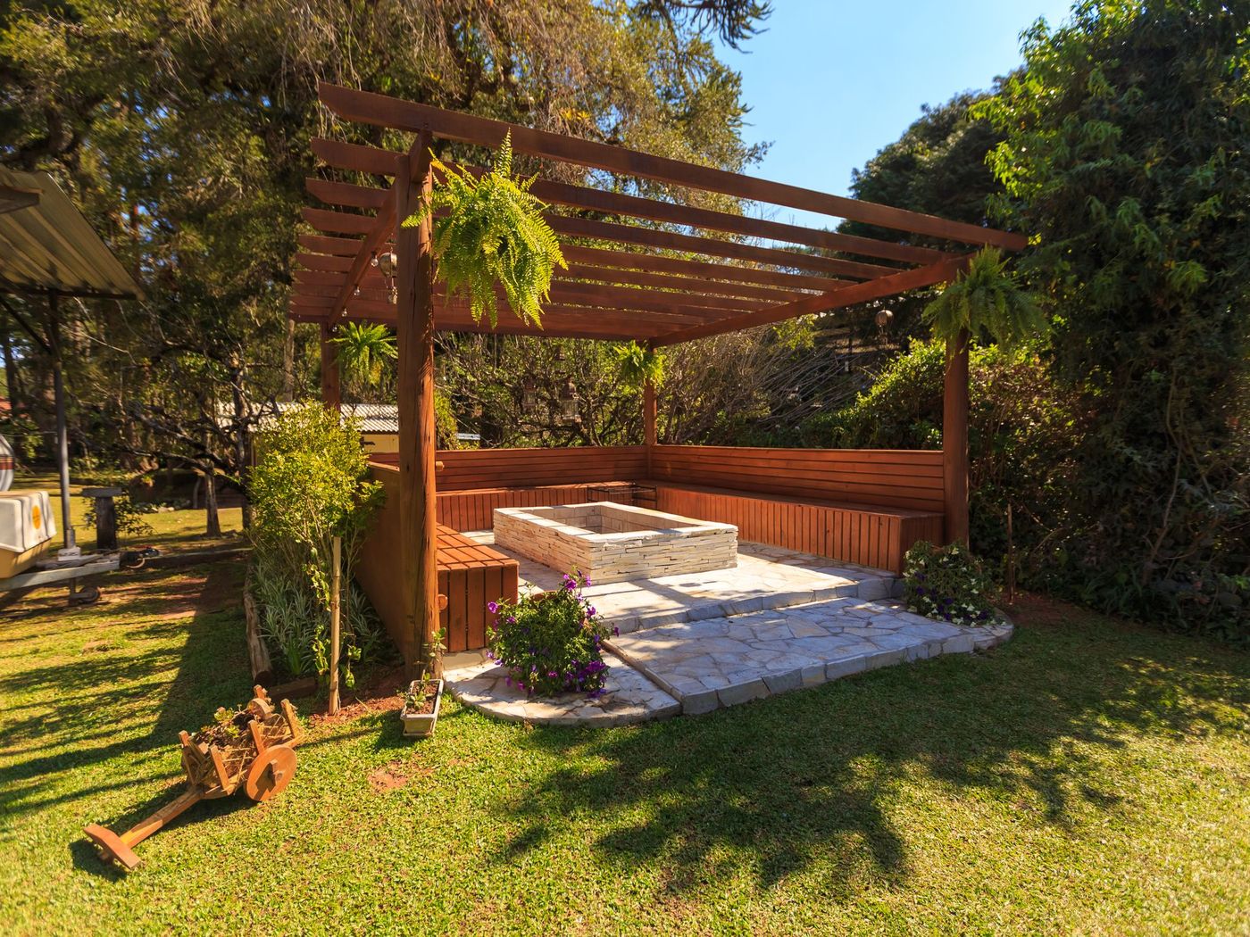 Cedar pergola over a stone patio in a green back yard