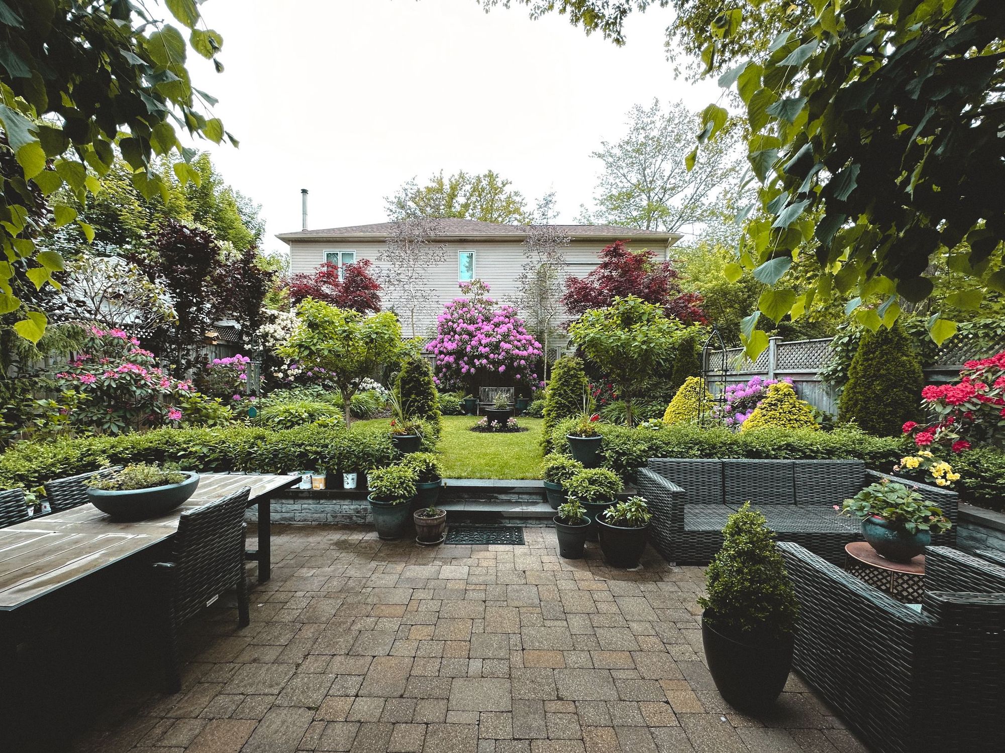 Paver patio with outdoor seating and flowering beds behind it