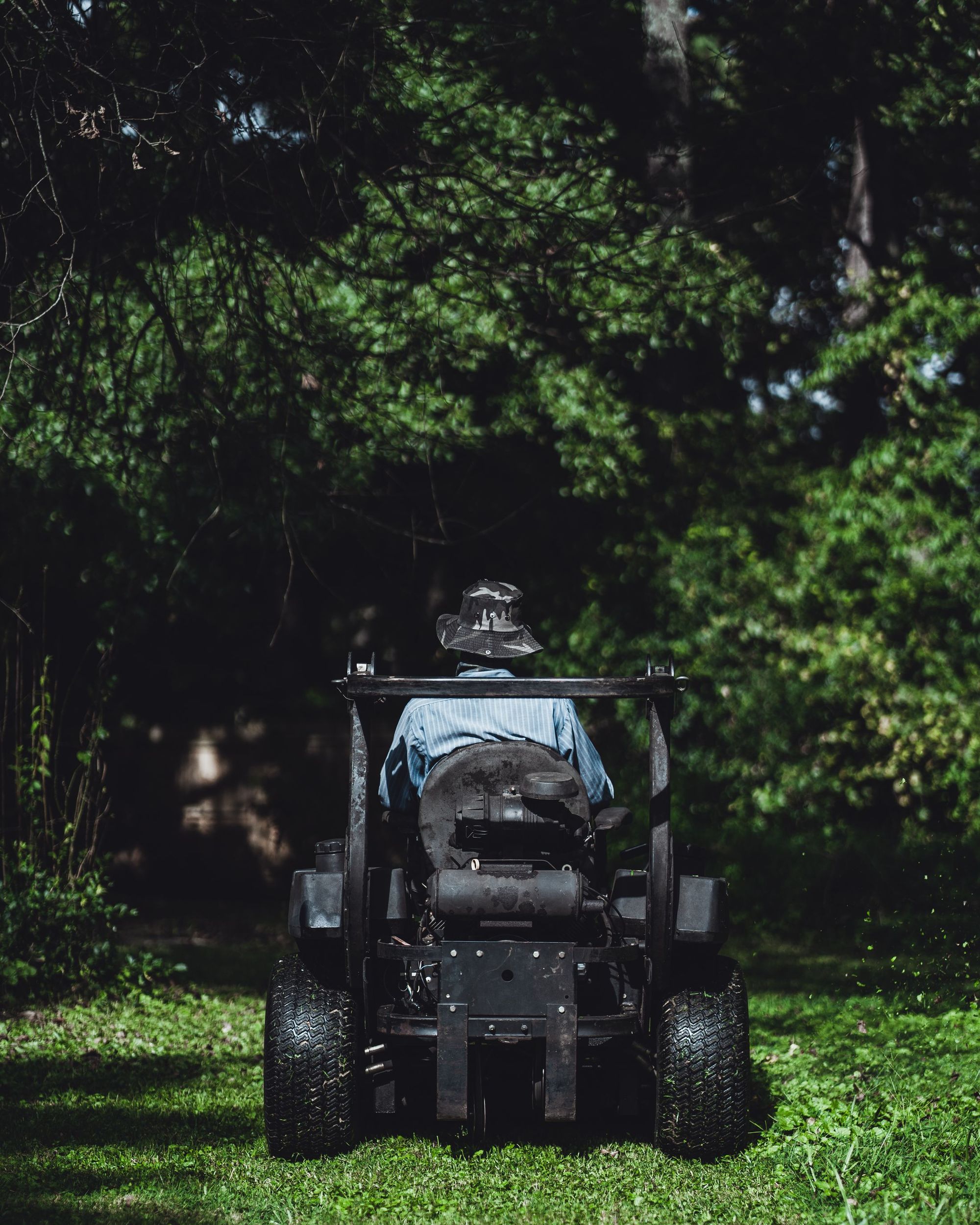 Mower parked on a shaded lawn under mature trees