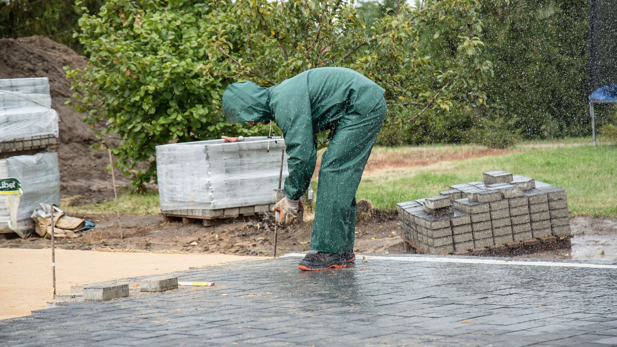 Crew setting pavers on a compacted base in a back yard
