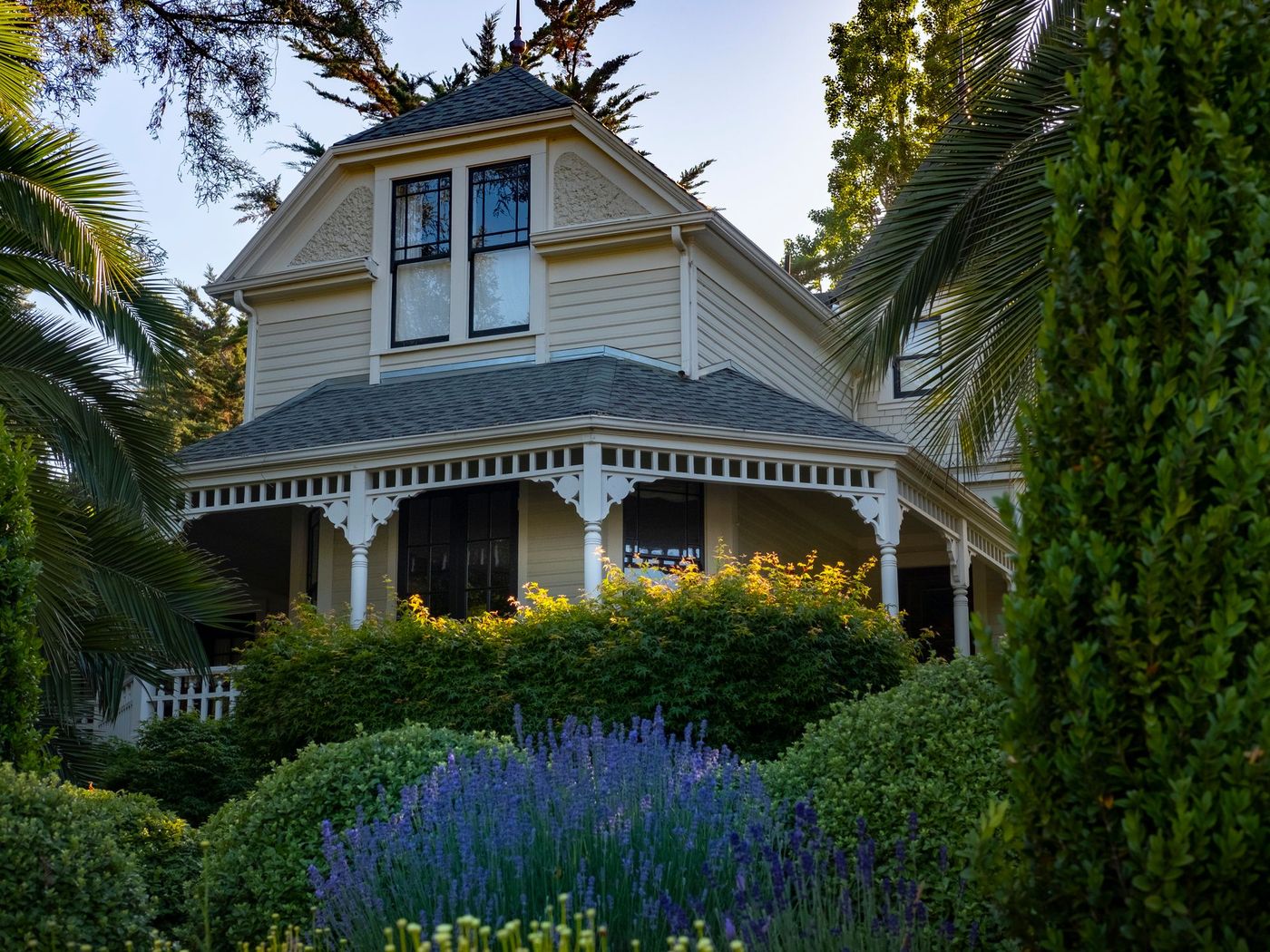 Porch of an older house behind lavender and clipped shrubs