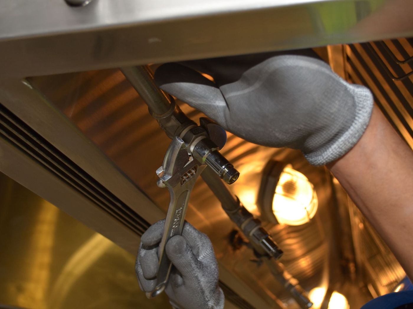 Plumber's gloved hands working under a sink by work light