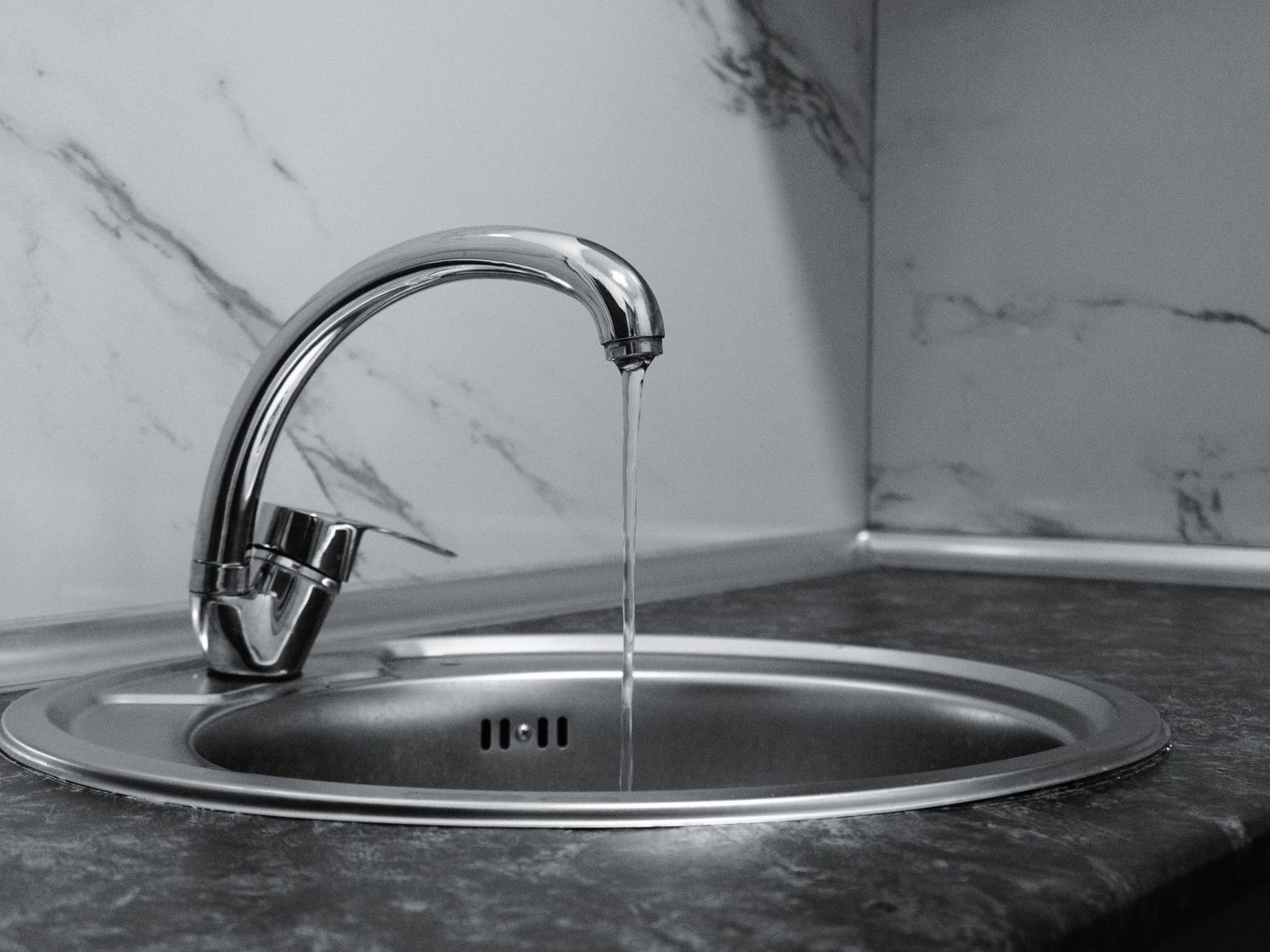 Chrome faucet on a marble backsplash