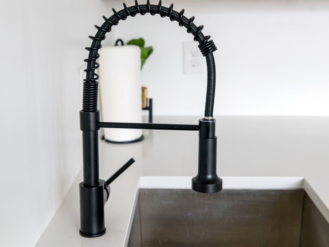 Chrome kitchen faucet running over a stainless sink