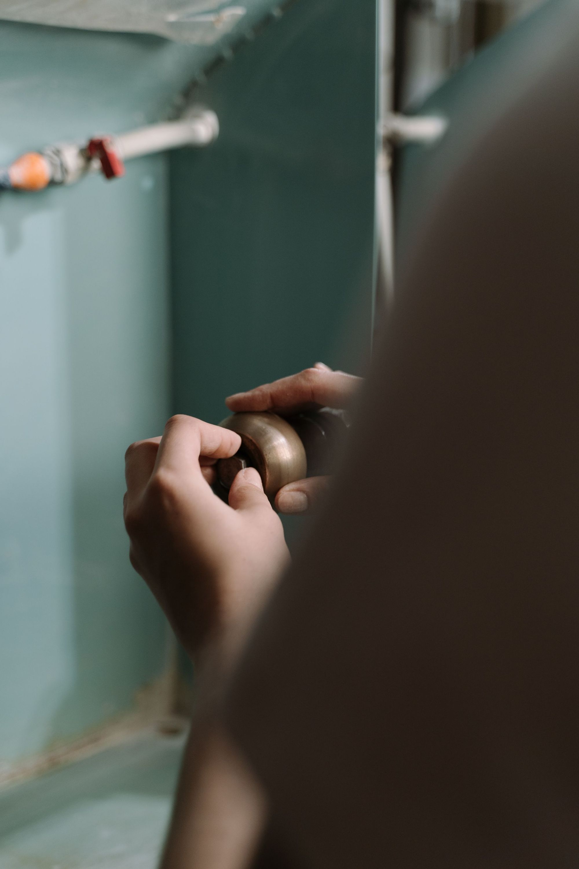Hands tightening a fitting under a kitchen sink