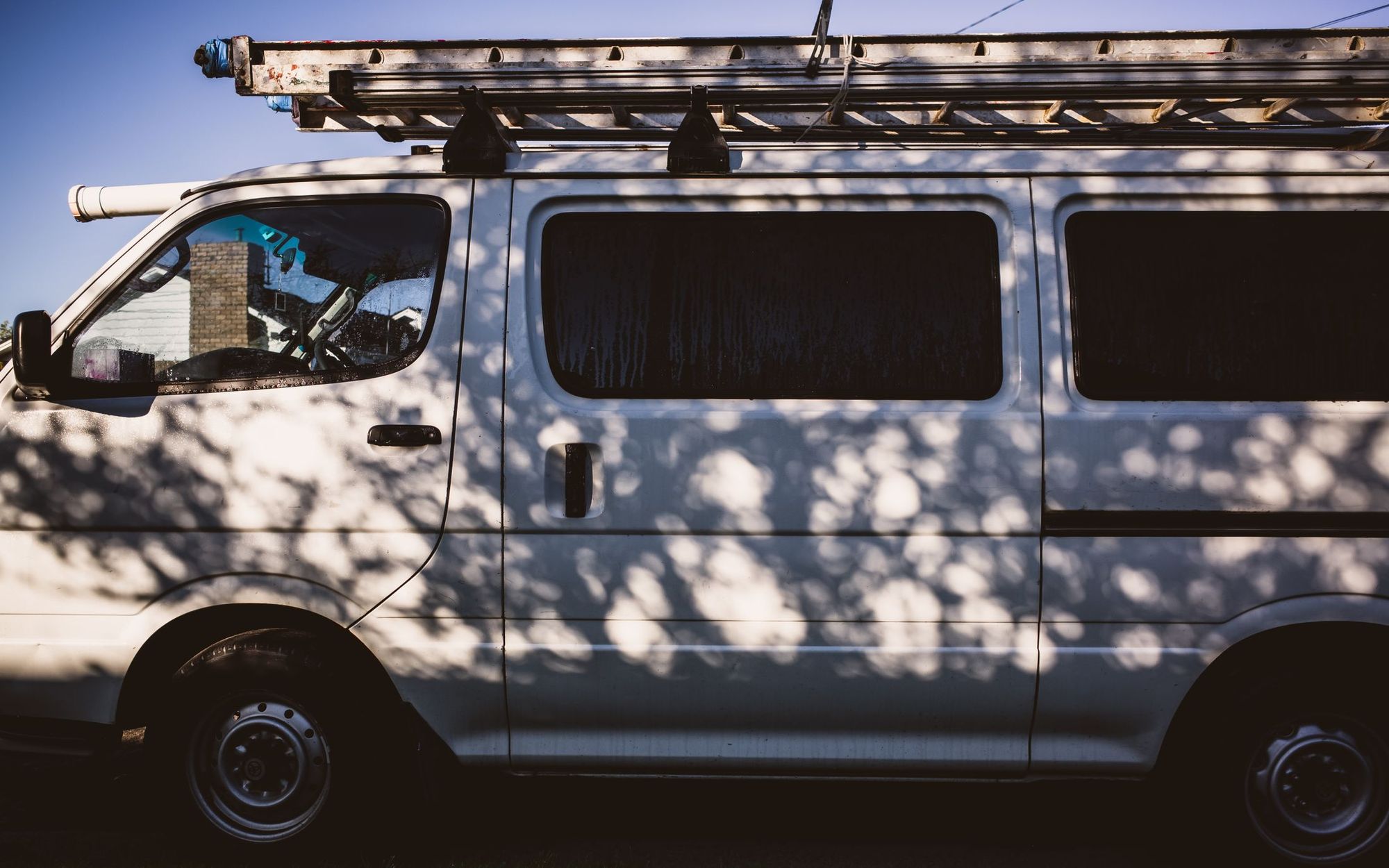 White service van parked under trees