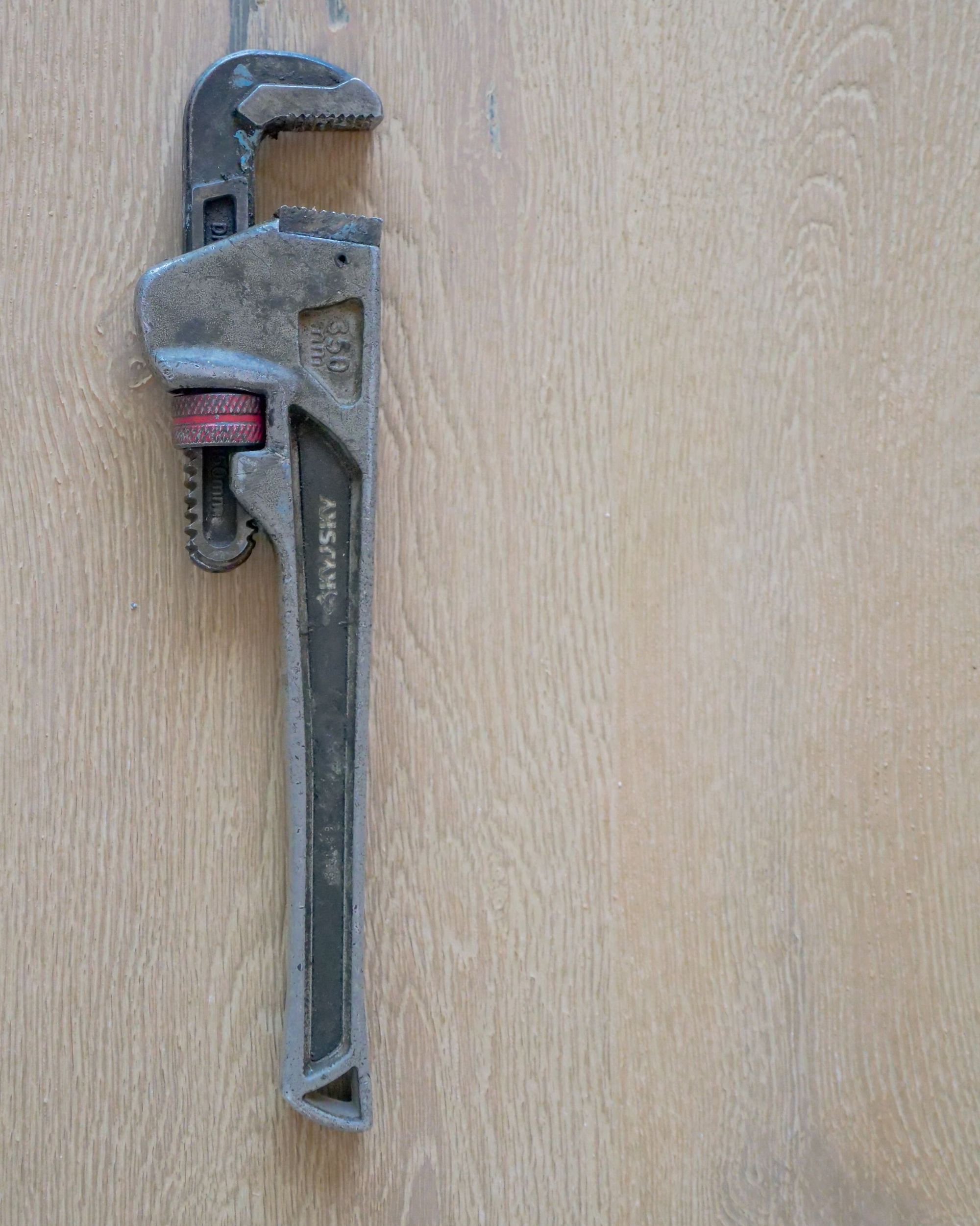 Pipe wrench hanging on a plank wall