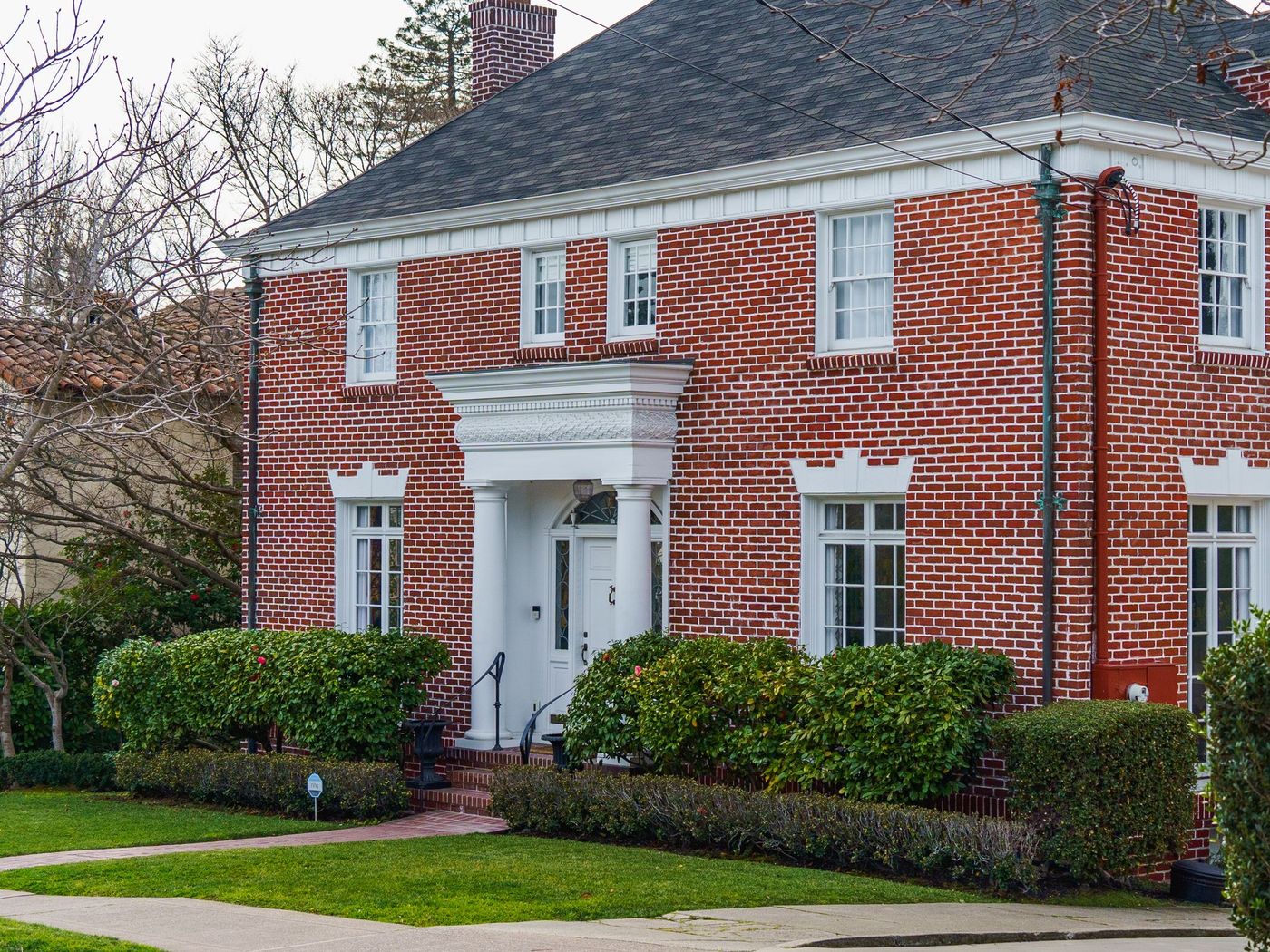 Brick two-story with a new roof, seen from the street
