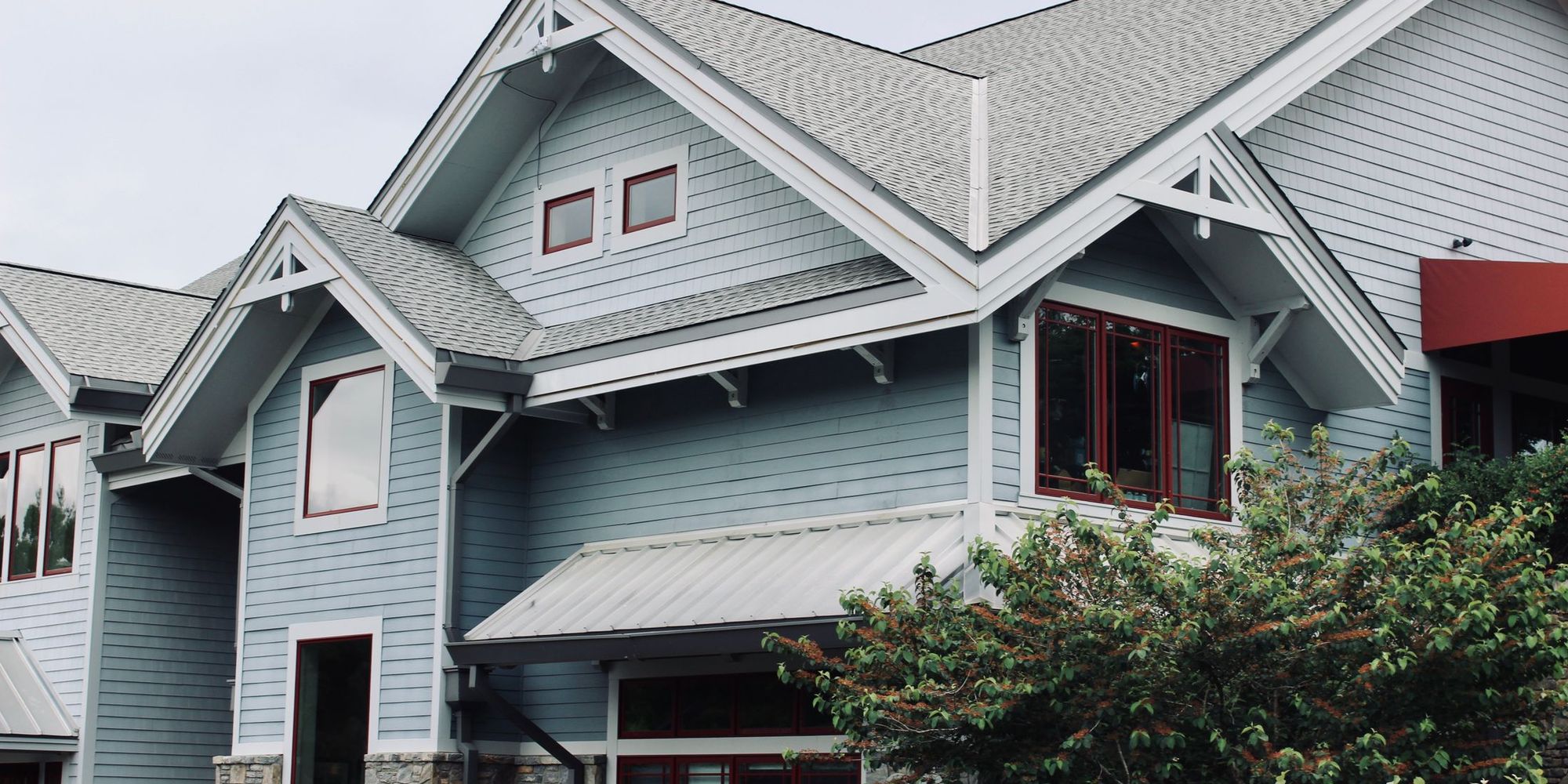 Blue craftsman house with a new architectural shingle roof, photographed from the street