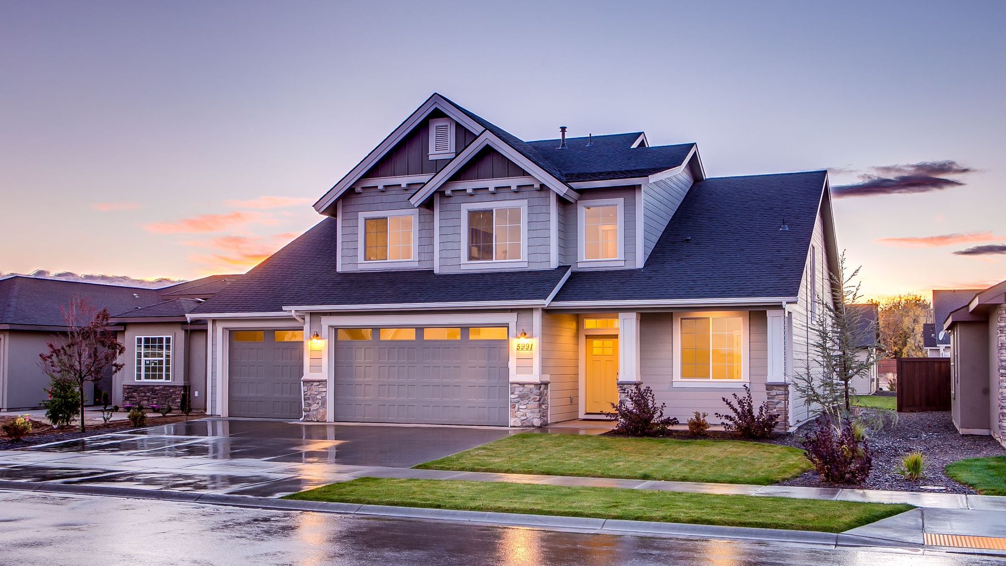 Two-story suburban house with a new steep shingle roof at dusk