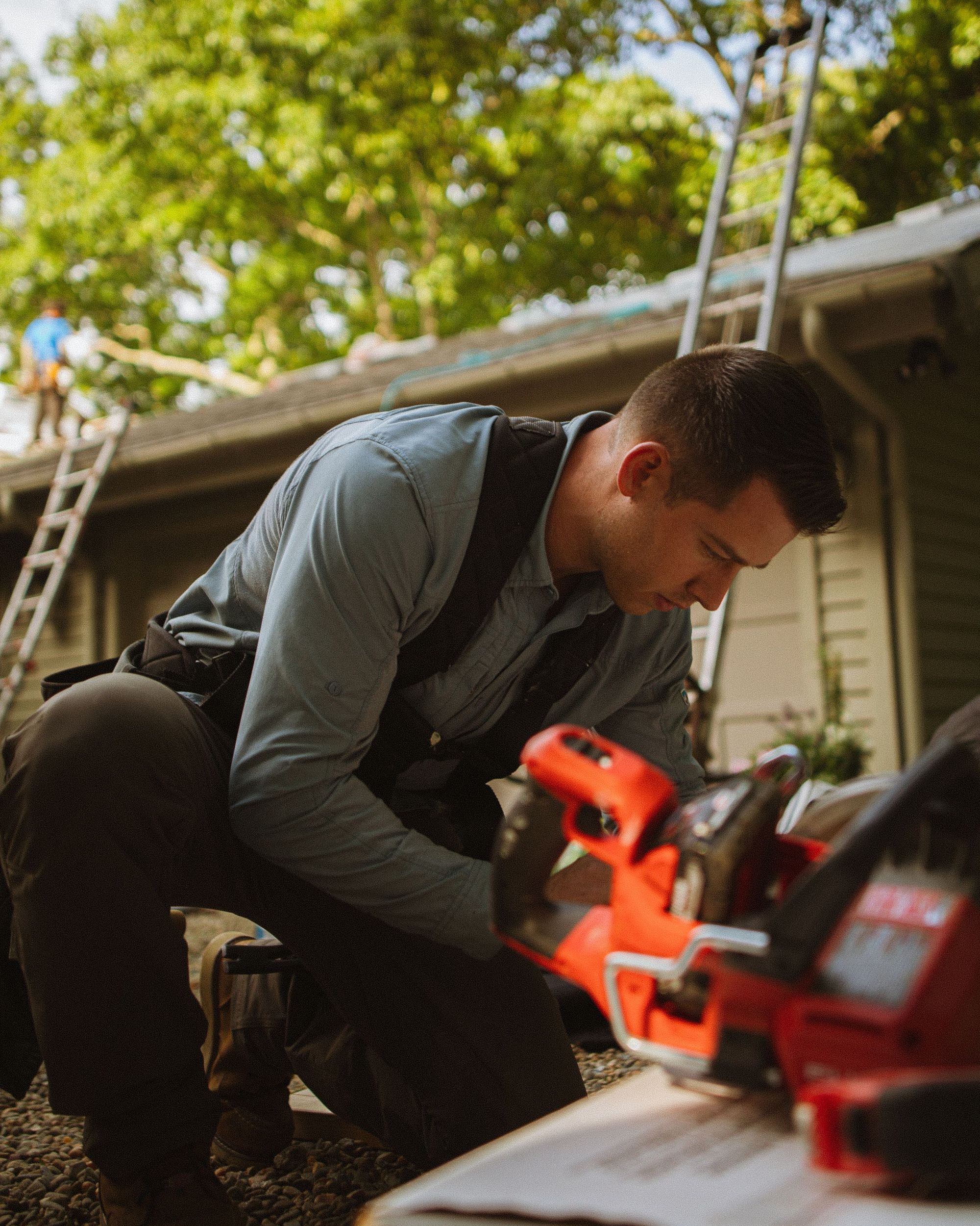 Tom Kessler, owner of Drip Edge Roofing Co., with a roofing nailer under the trees at a Cornelius house